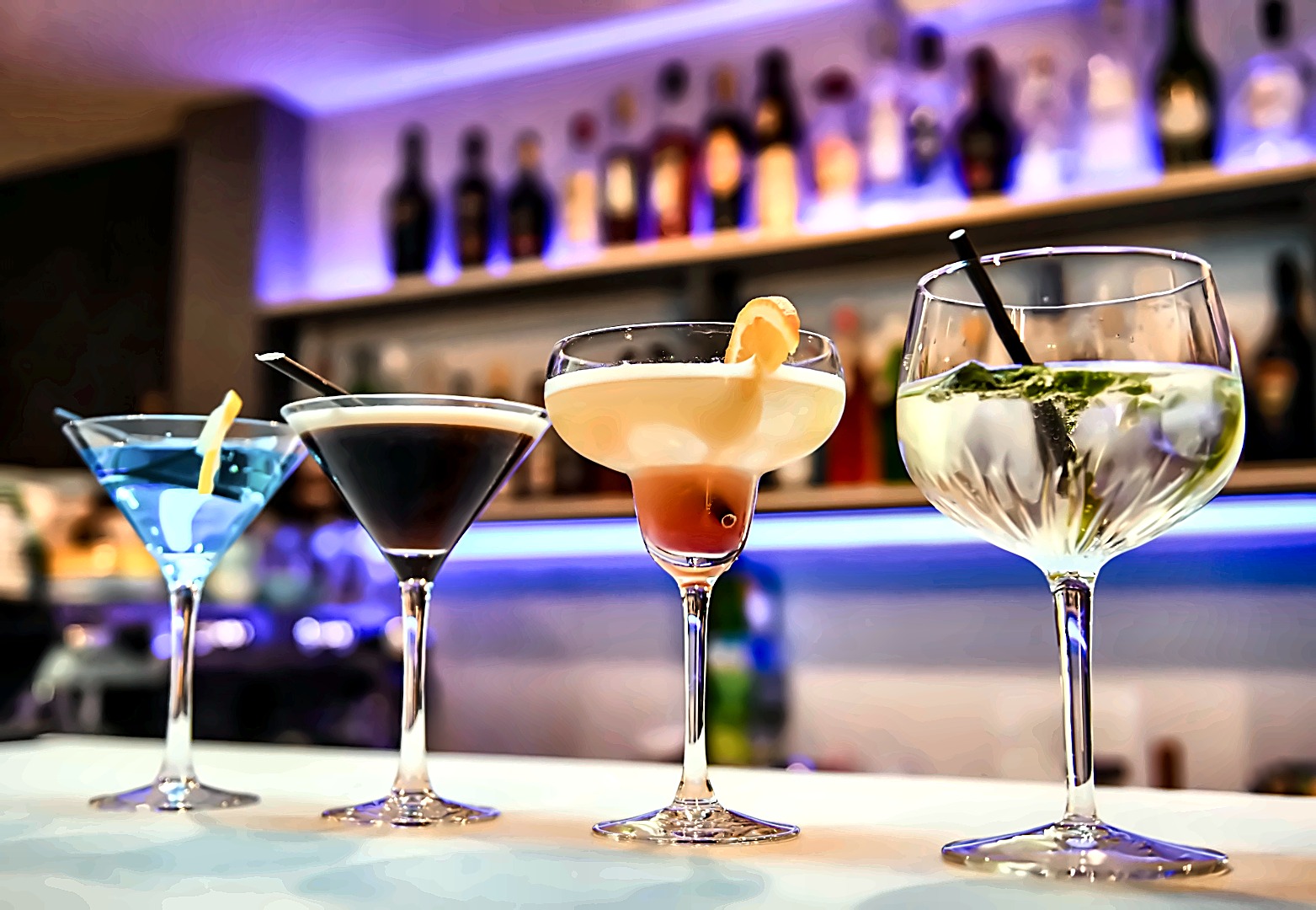 A line-up of cocktails at the bar under ambient lighting