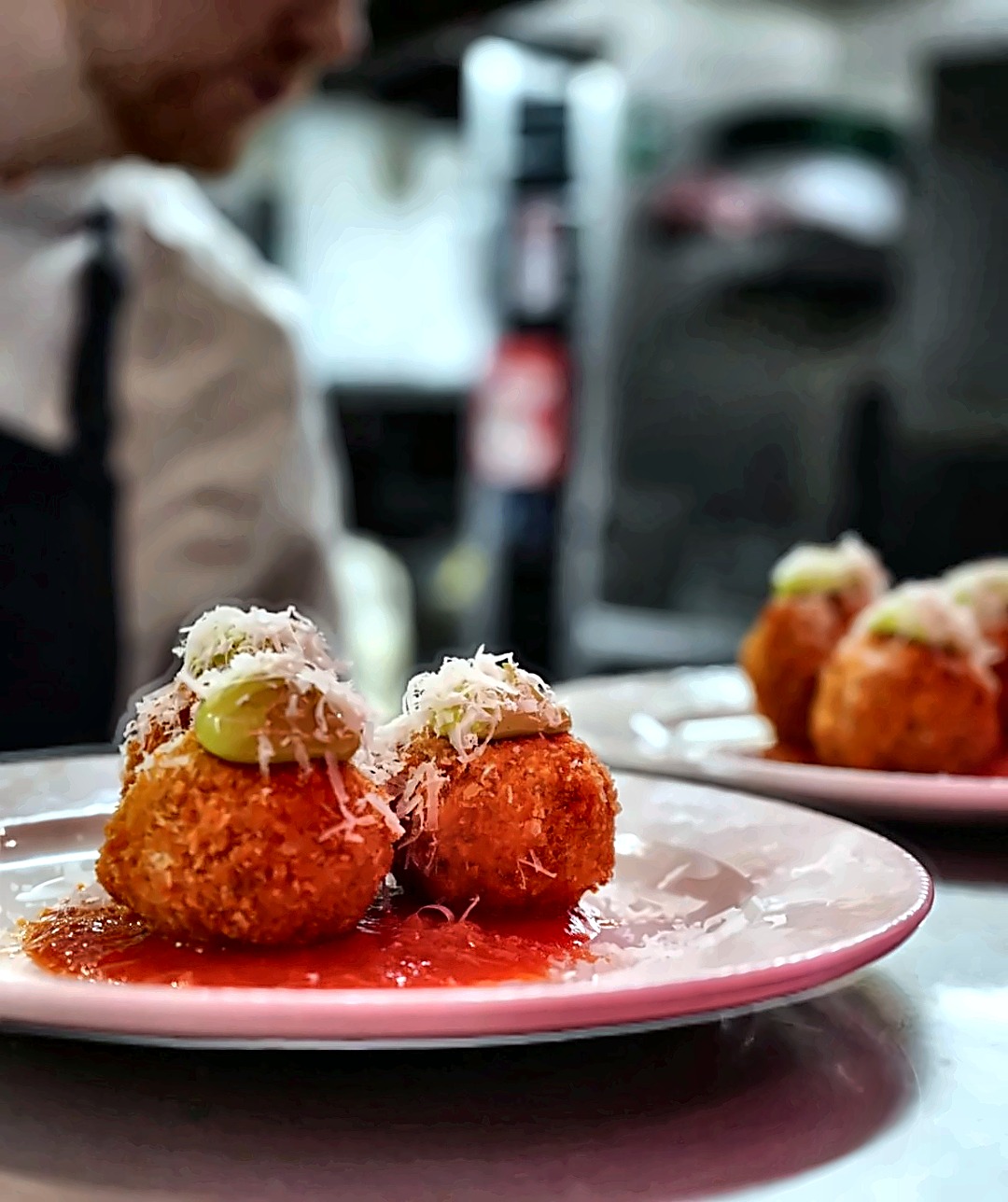 Arancini topped with shaved parmesan and basil puree