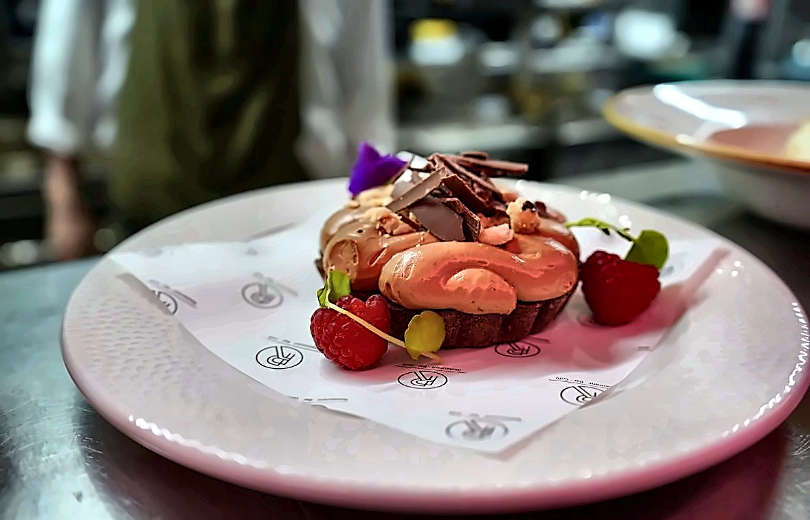 Chocolate and raspberry tart on a branded plate